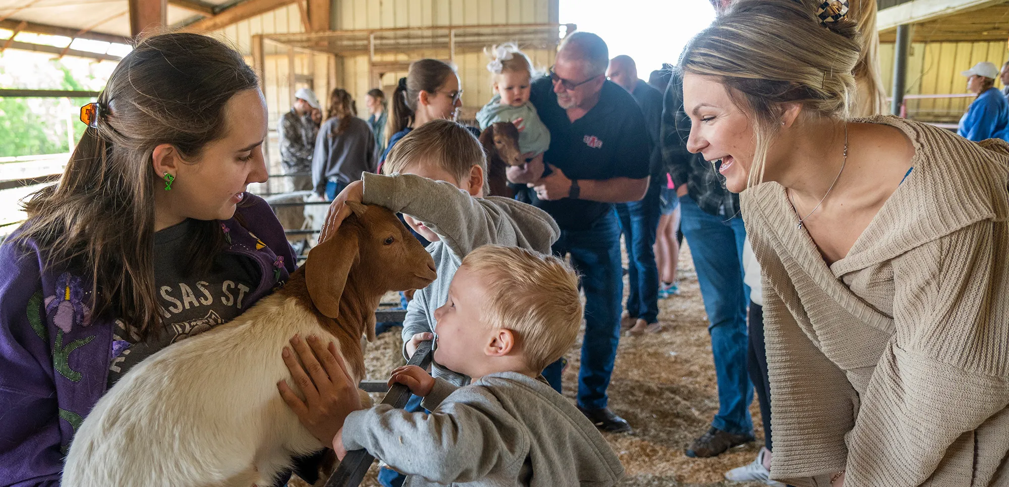 A student holds a goat for kids to pet