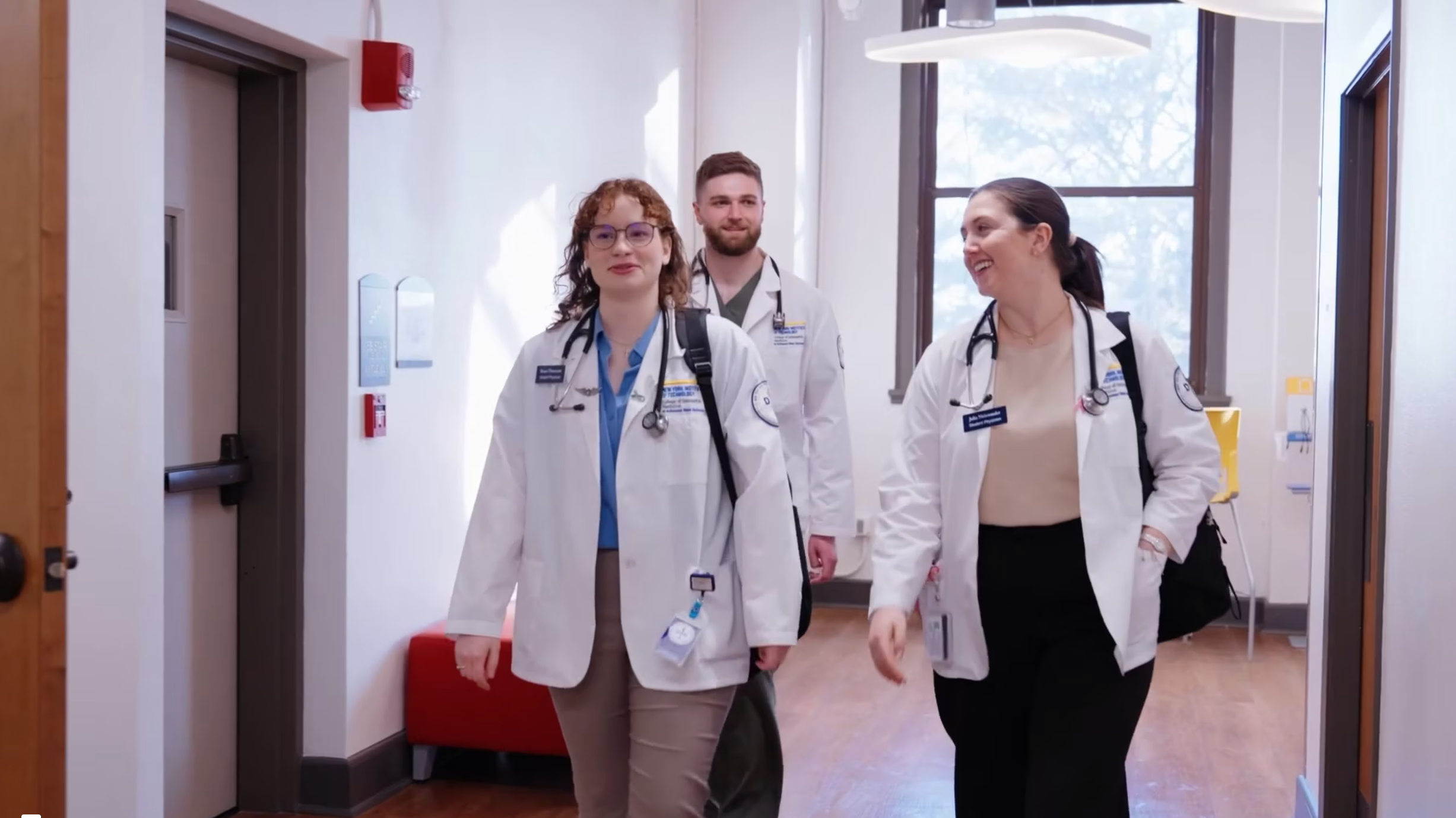 Medical students walk down a hallway at NYITCOM