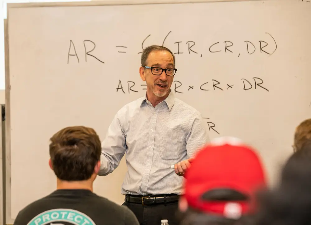 professor teaching class about accounting formulas