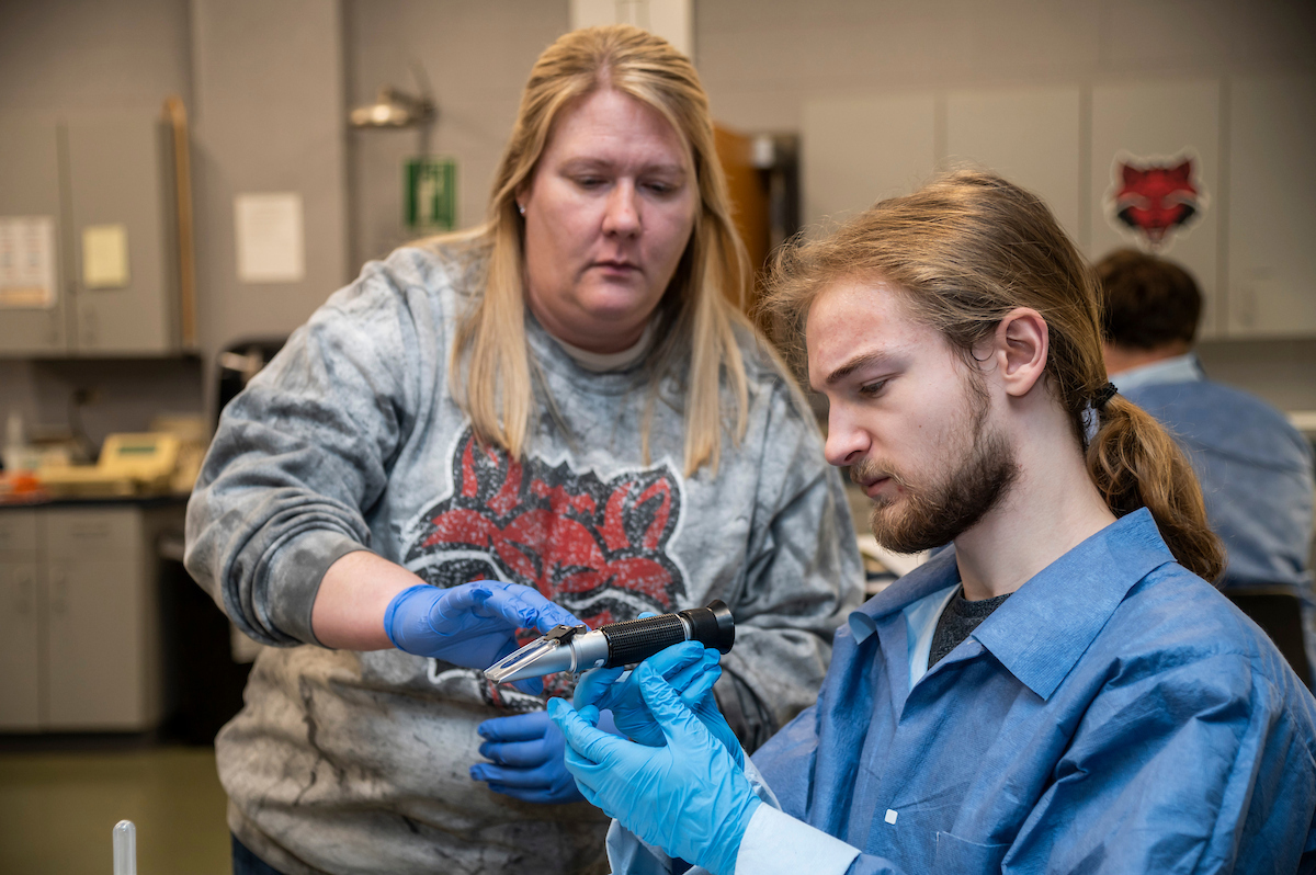 An instructor assists a student with a hands-on science lab demonstration.