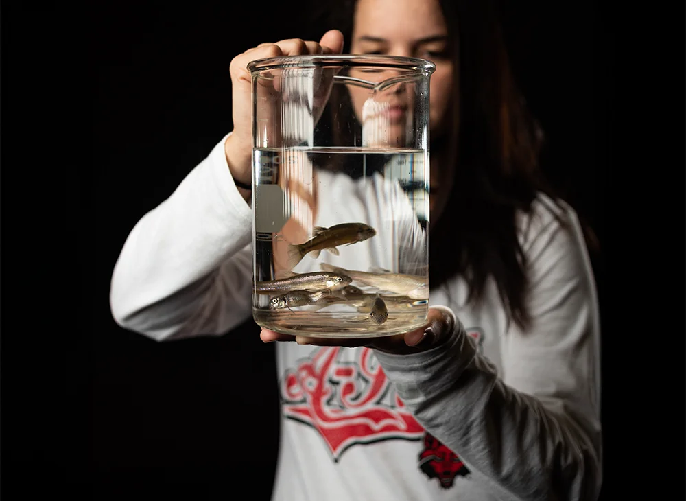 A student with a beaker of fish