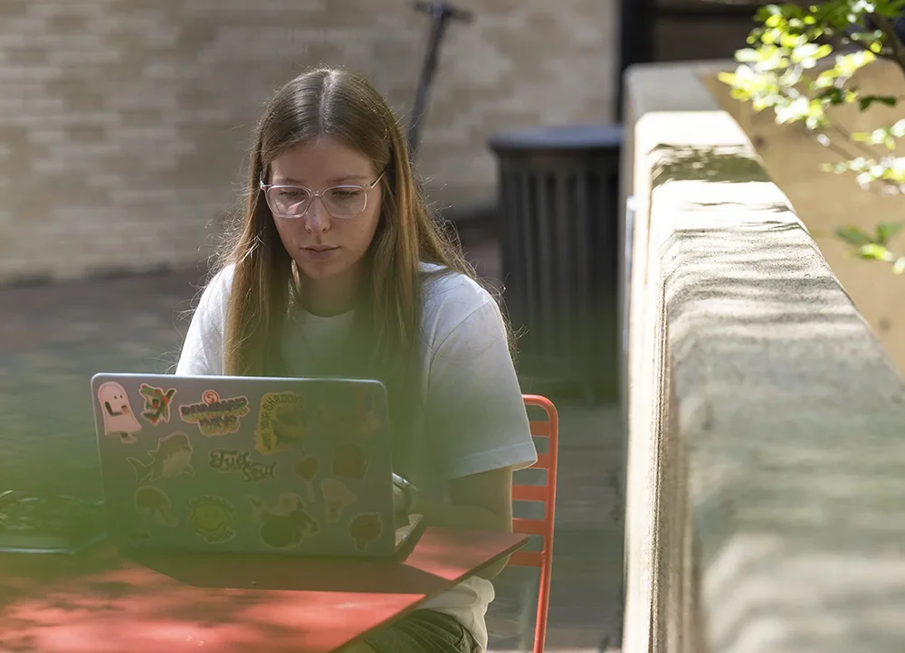 Student sitting outside and working on laptop.