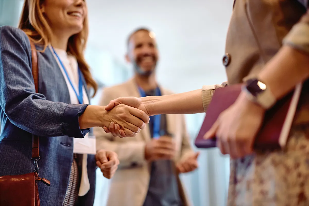 smiling woman shaking hands while third smiling person watches