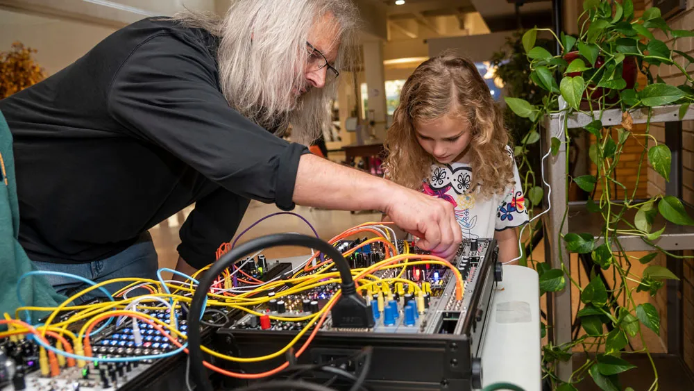 professor demonstrates making musical sounds using wires and electrical circuits