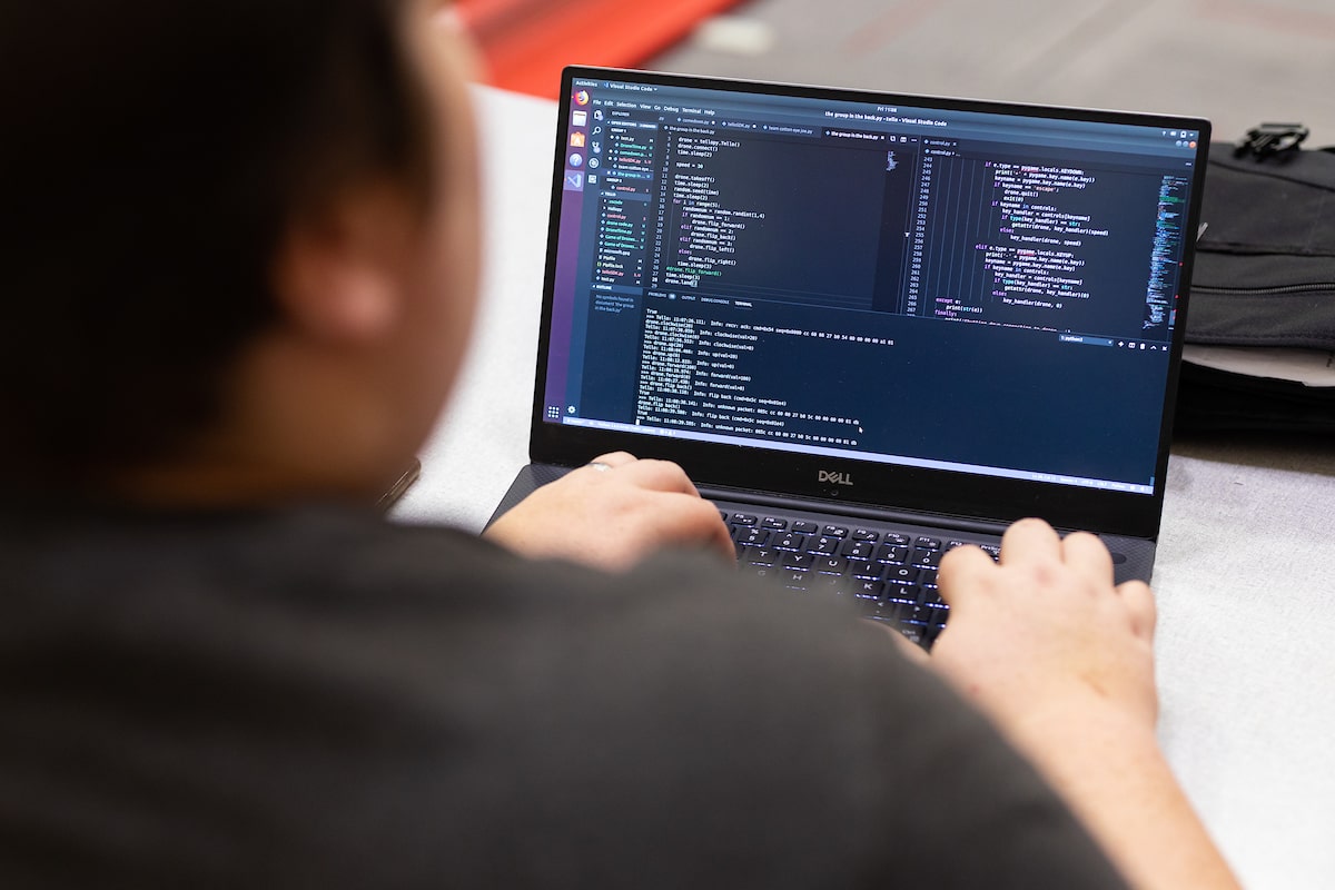 Students use computer code to program a drone.
