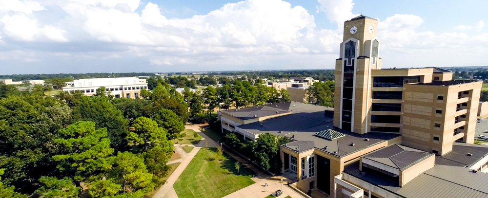 A drone photo of the Dean B. Ellis Library with the campus and a blue sky in the background