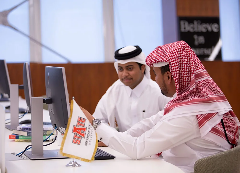 Two students at the Qatar campus studying at computers.