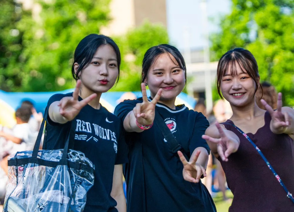 a-state international students giving a peace sign on campus