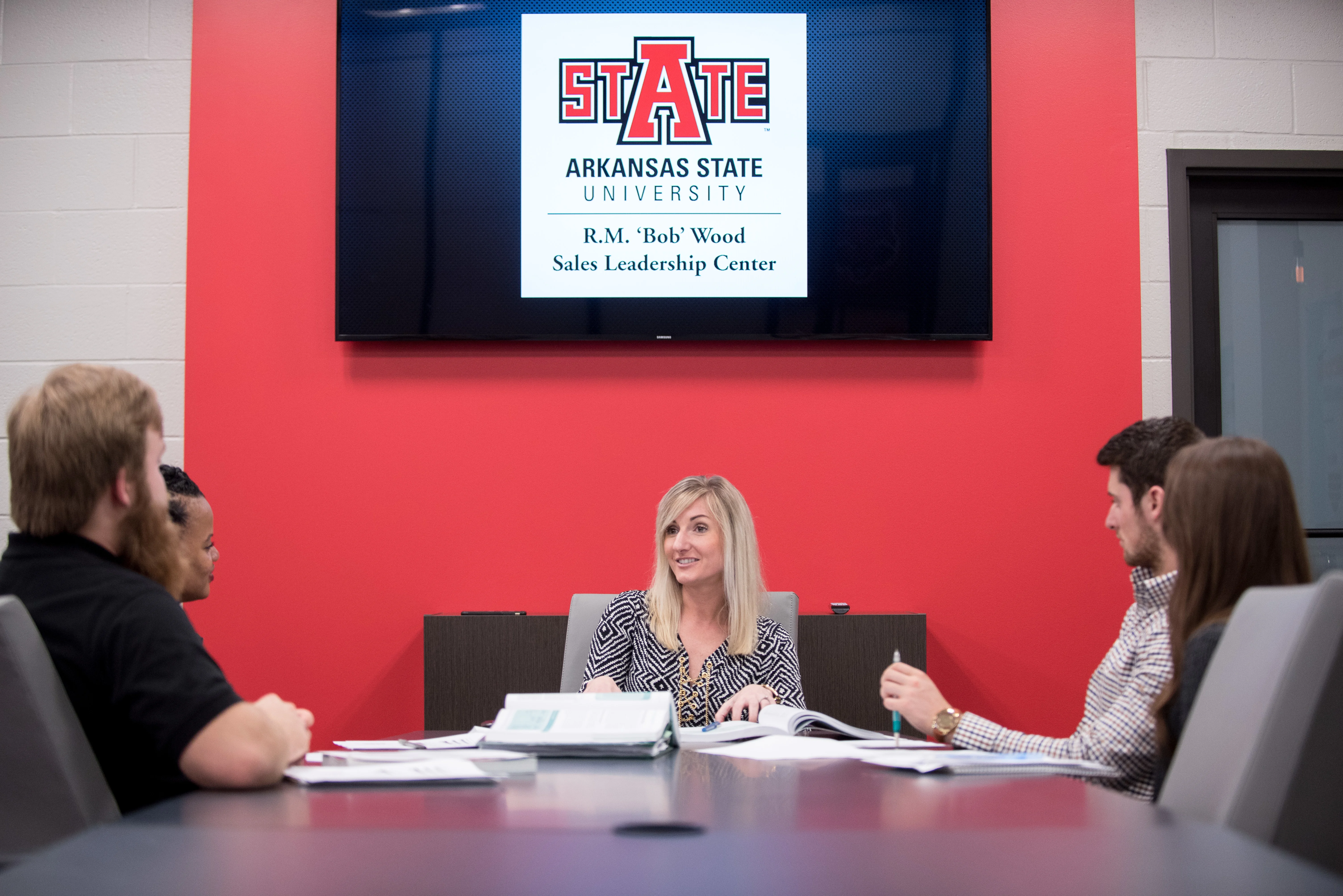 Two students walking away from camera with red backpacks with Red Wolf patches on them.