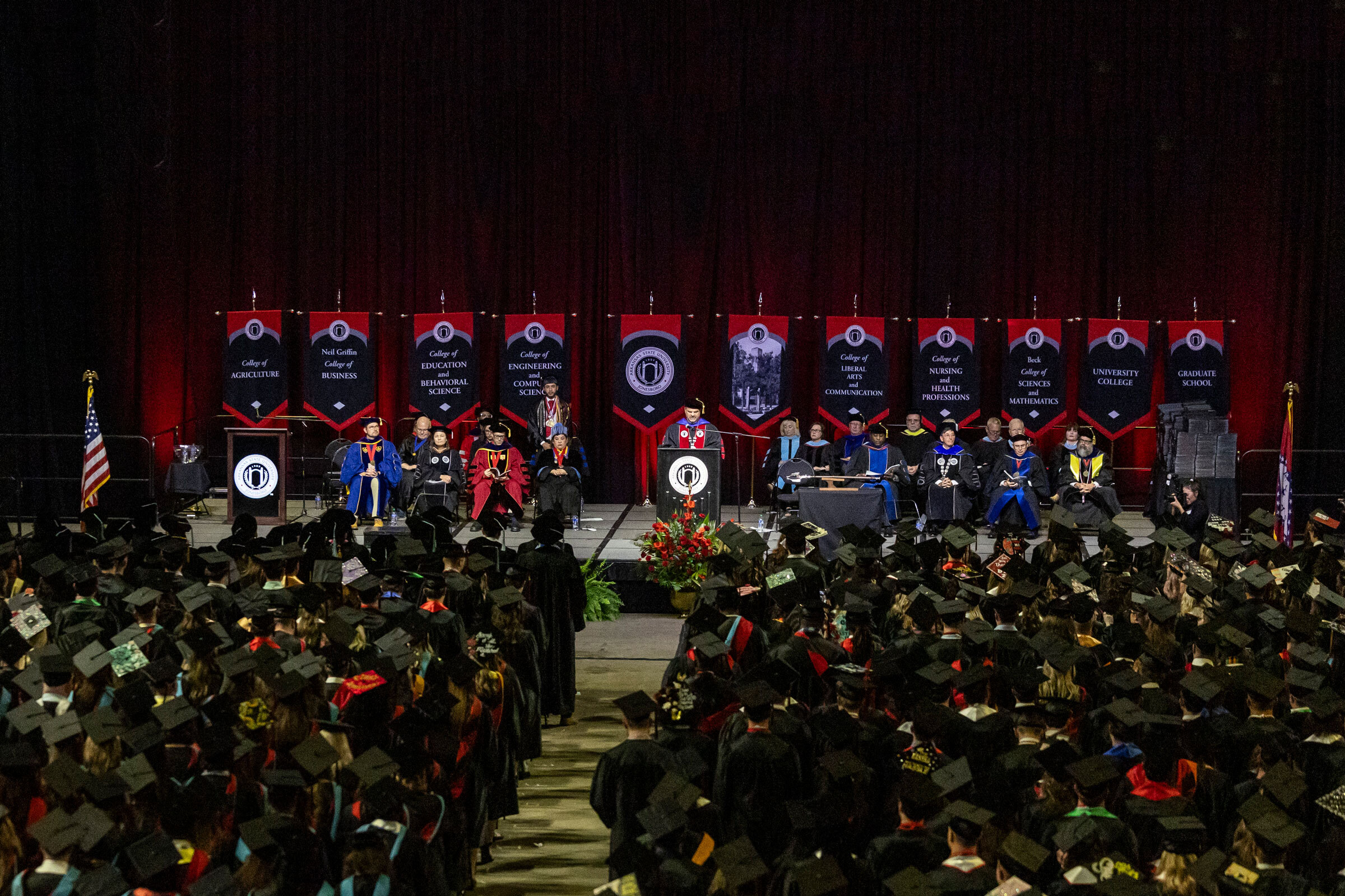 The A-State leadership team and Board of Trustees sit on the stage at a recent commencement ceremony.