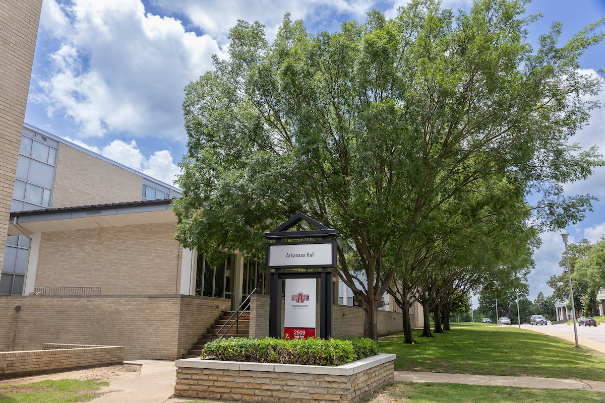 Exterior of Arkansas Hall at A-State with trees, brick steps, and campus signage on a sunny day.