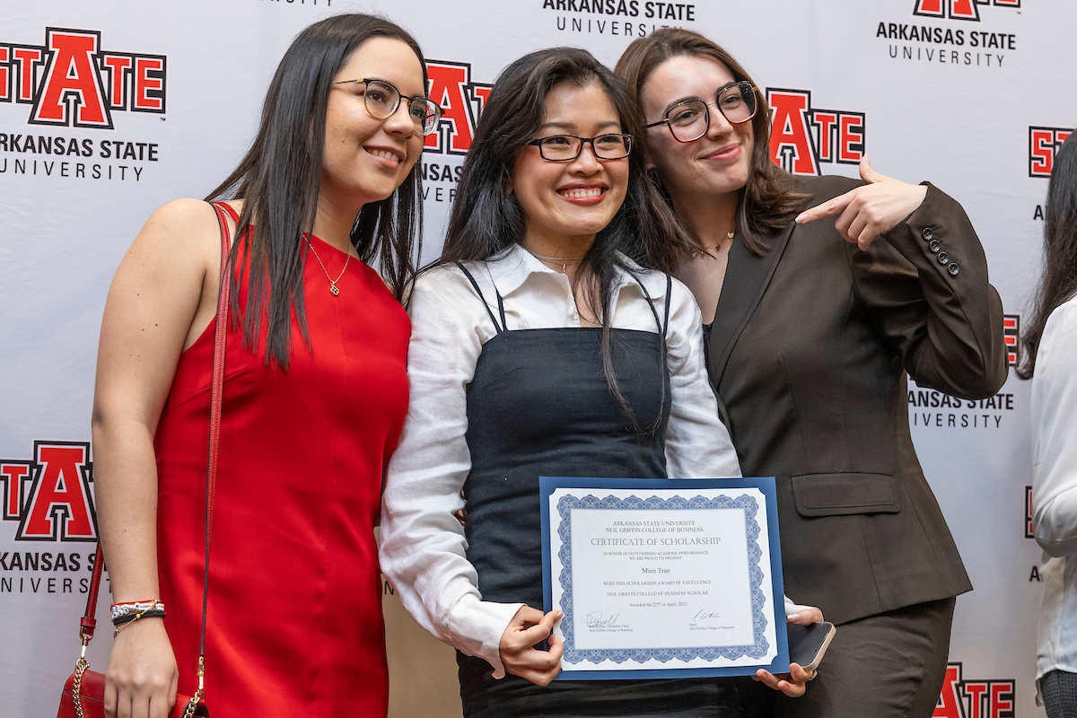An A-State student is joined by her friends and she shows off a certificate.