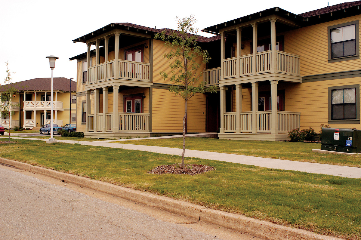 Traditional-style student housing buildings with covered balconies and green lawn at A-State.