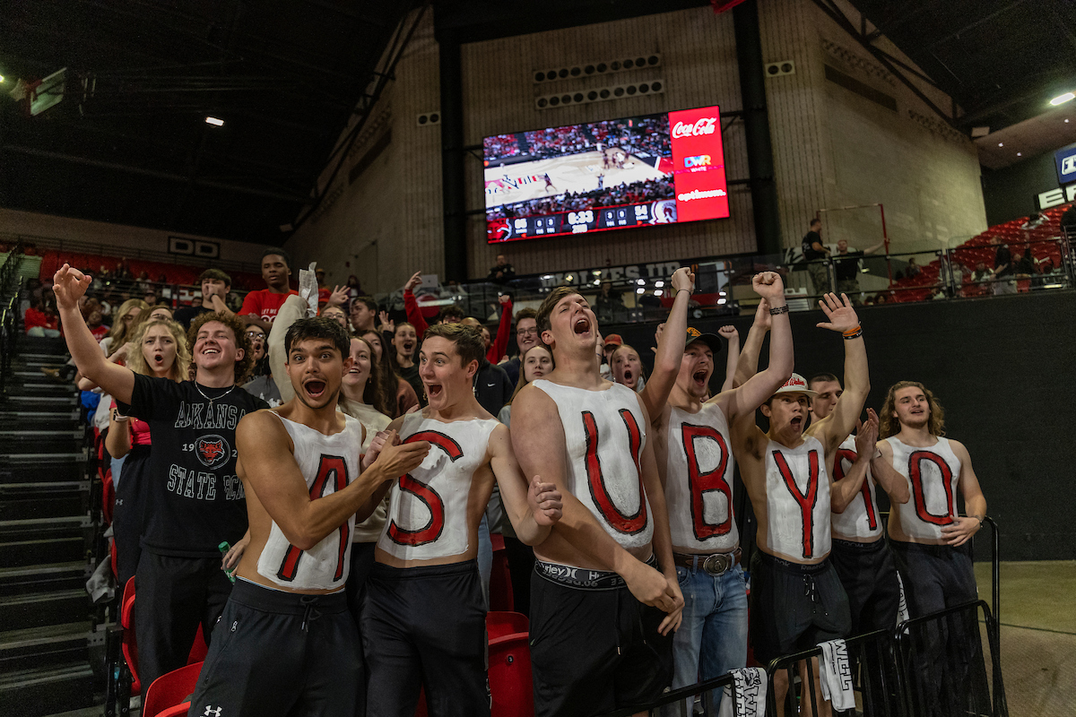 Students in body paint celebrate a three made during a basketball game.