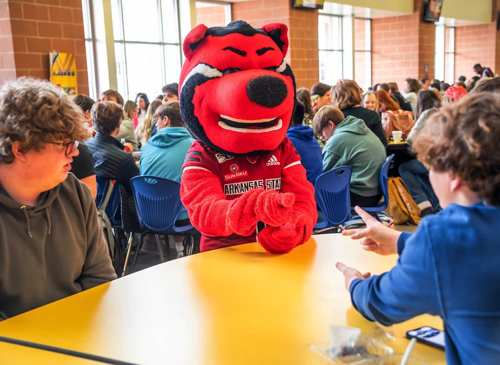 Howl sitting at a school table with high school students.