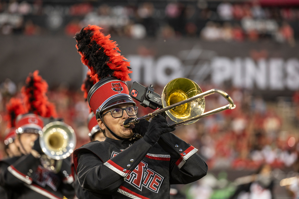 A student band member plays the trombone at halftime during an A-State football game.