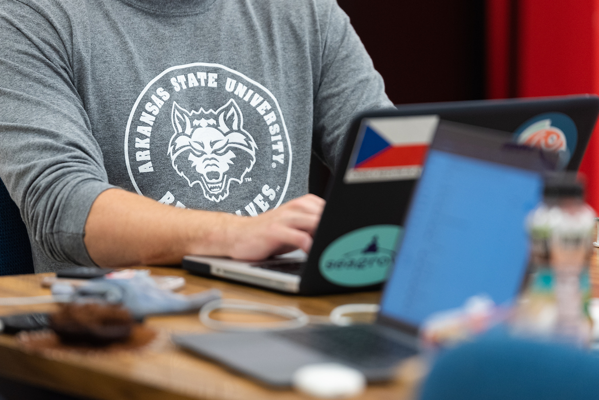 Student working on laptop in Red Wolves shirt