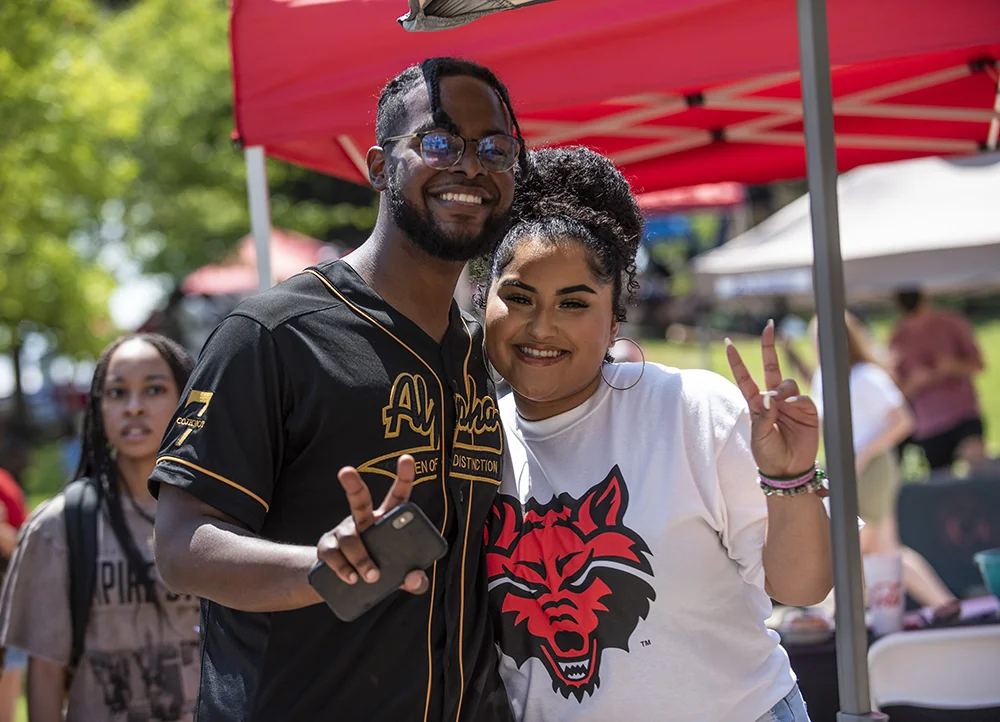 Two students holding up peace signs at an event on campus.