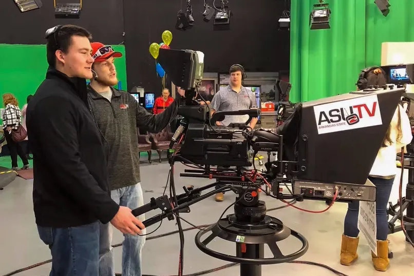 Students operate TV camera in ASU studio during a live production session.