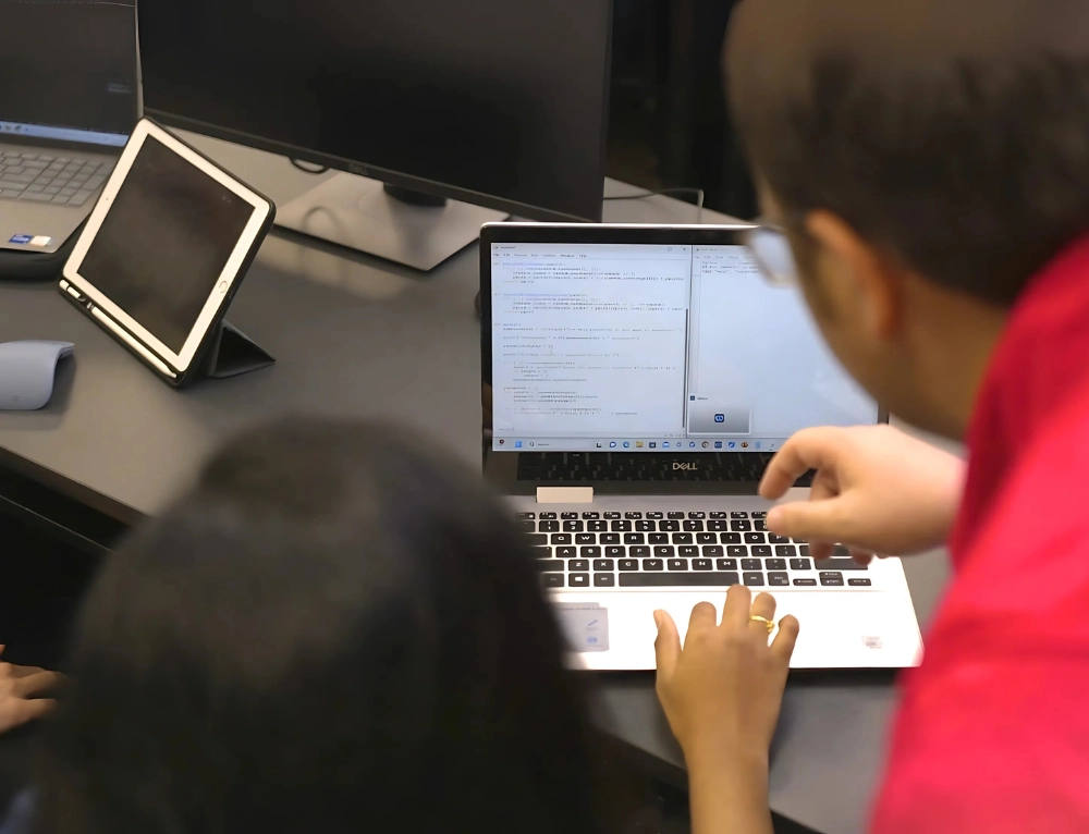 Computer Science student and teacher programming on a laptop.
