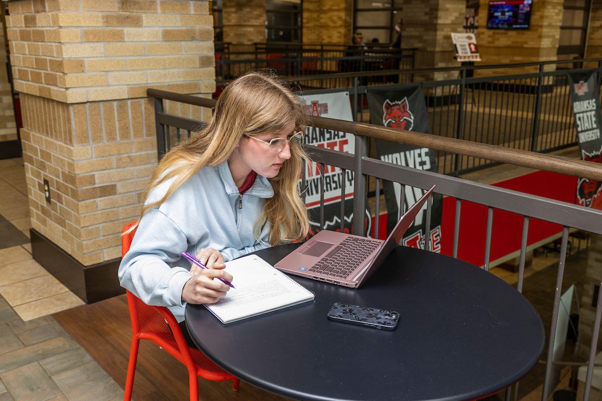 An A-State student works on a laptop in the Reng Student Union atrium.