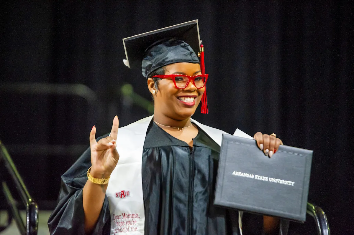 A recent graduate smiles as she crosses the stage at commencement.