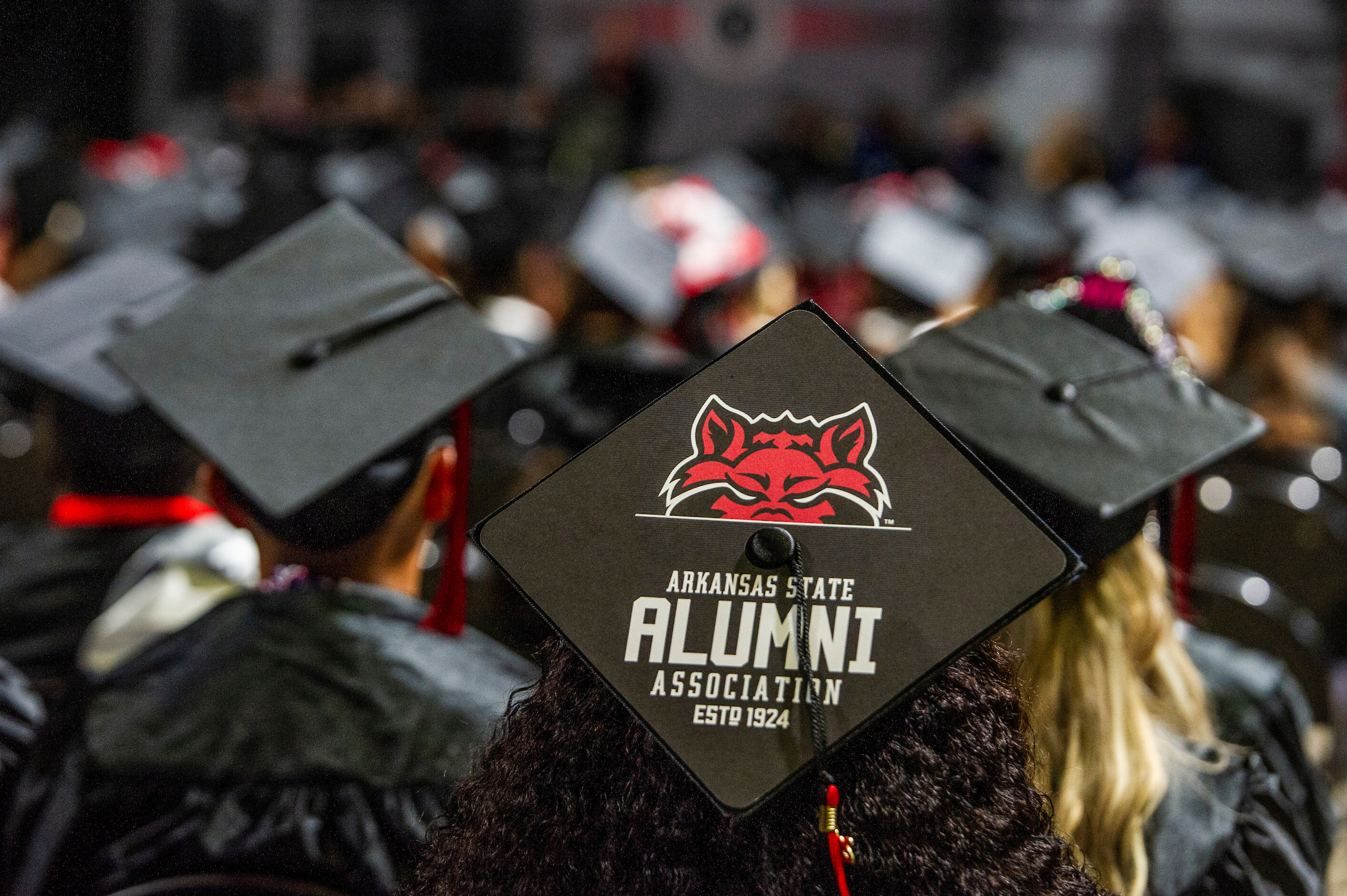 Close-up of graduation cap featuring the Arkansas State Alumni Association logo.