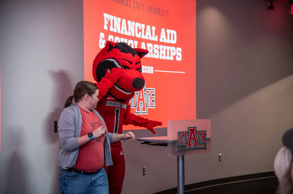 Red Wolves mascot Howl poses with a tour guide near the podium during a financial aid and scholarships event.