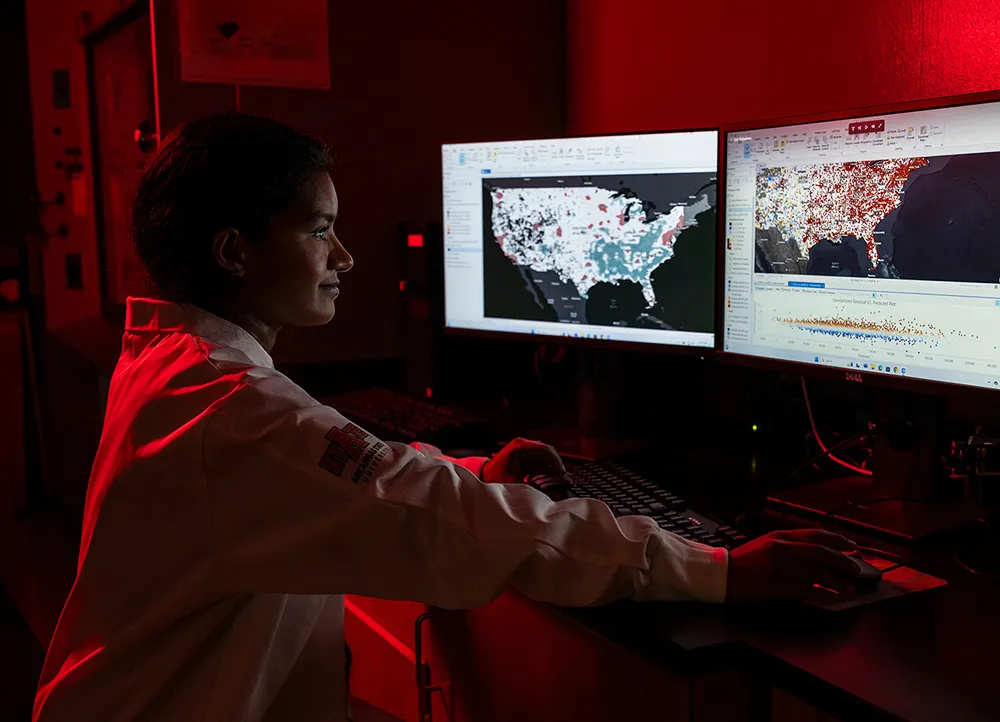 researcher studies data on computer screens