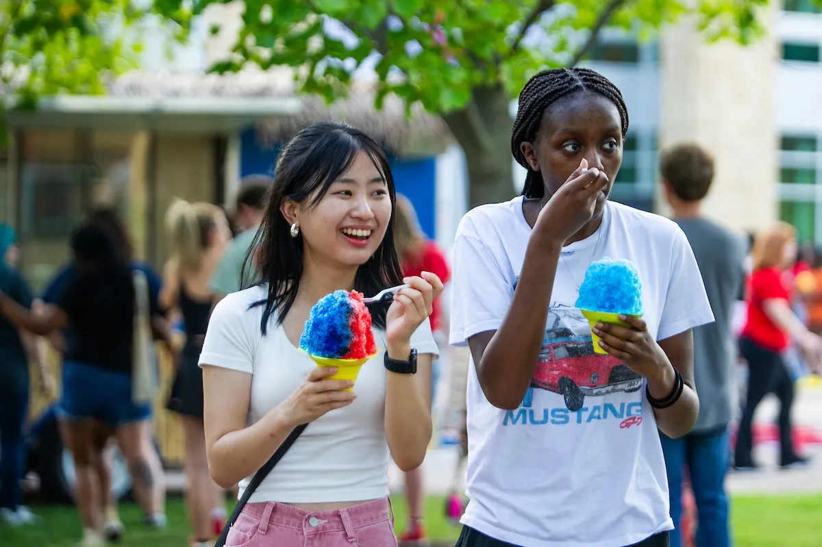 Students enjoy snow cones on the Heritage Plaza Lawn during a campus student life event.