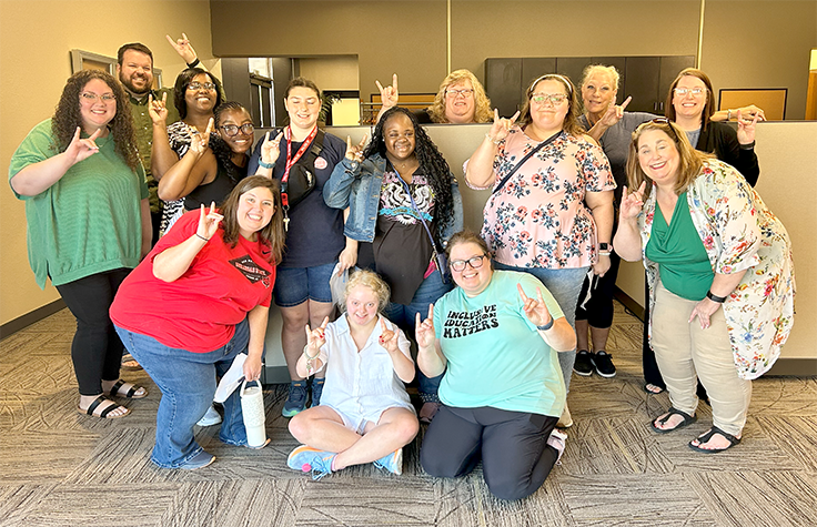 RESTORE HUB members pose with H.O.W.L. transition program students while giving a wolves up hand sign